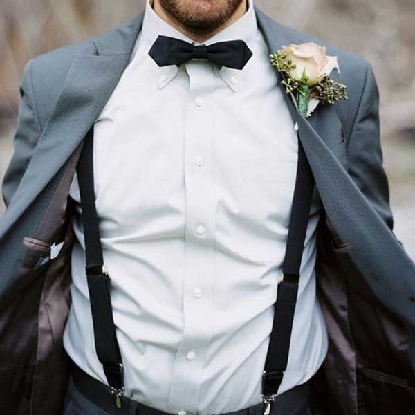 Homme en costume avec bretelles et boutonnière.