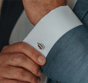 Homme ajustant une manchette de chemise avec bouton de manchette argenté.