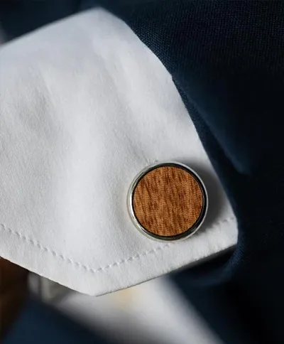 Bouton de manchette en bois sur une chemise blanche et veste bleue.