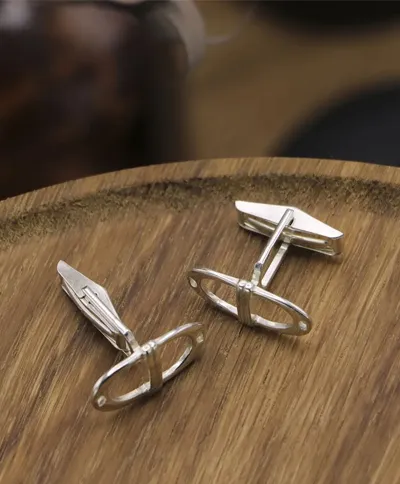 Boutons de manchette en argent sur une surface en bois.